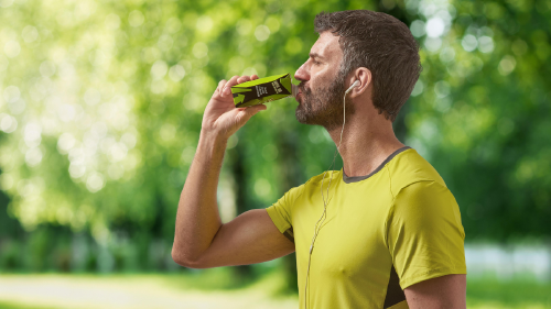 4 razones envase carton opcion segura responsable bebidas alimentos Hombre deportista bebiendo de un envase de cartón para bebidas sobre fondo verde