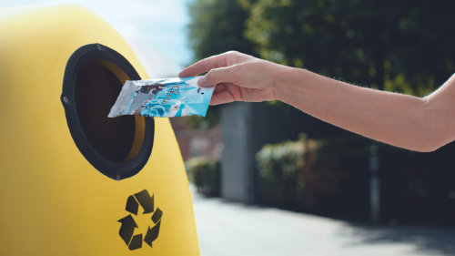 economia circular que es beneficios consumidores empresas Mano arrojando cartón bebidas en contenedor amarillo